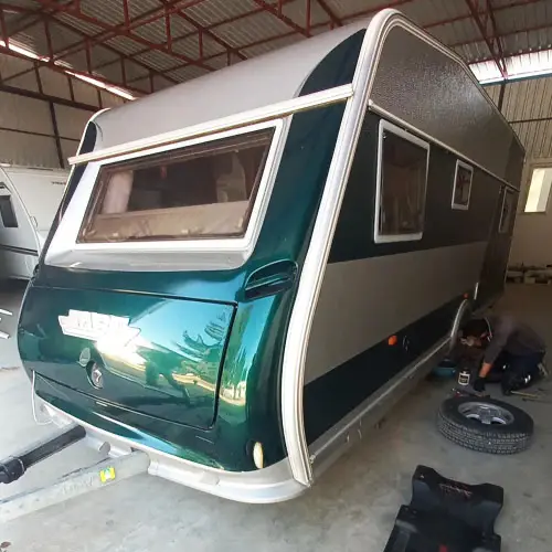 Atölyede yenilenen yeşil karavan ve altında çalışan usta
